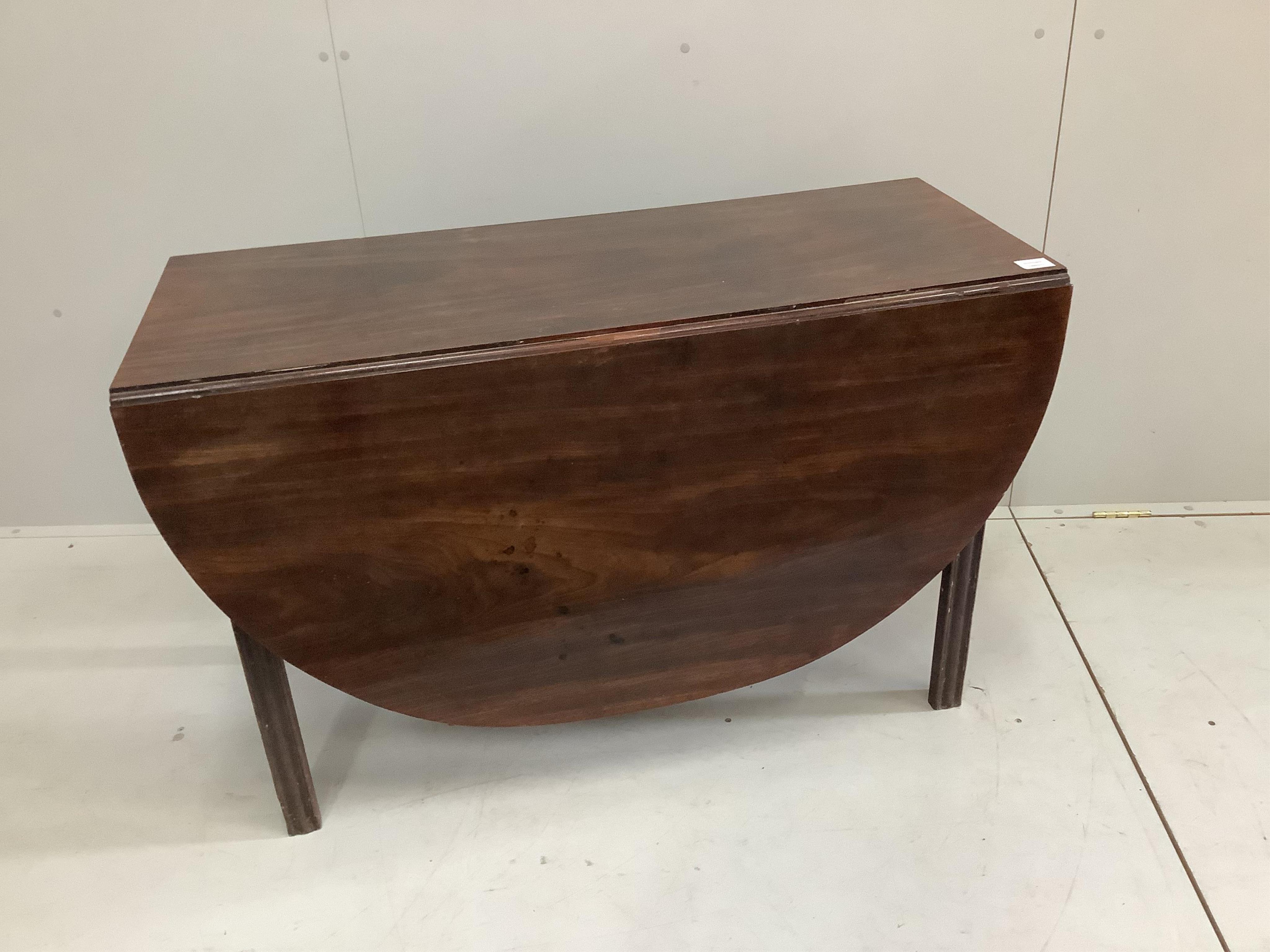 A George III oval mahogany drop leaf extending dining table, on pad feet, width 114cm, 156cm extended, height 70cm. Condition - fair